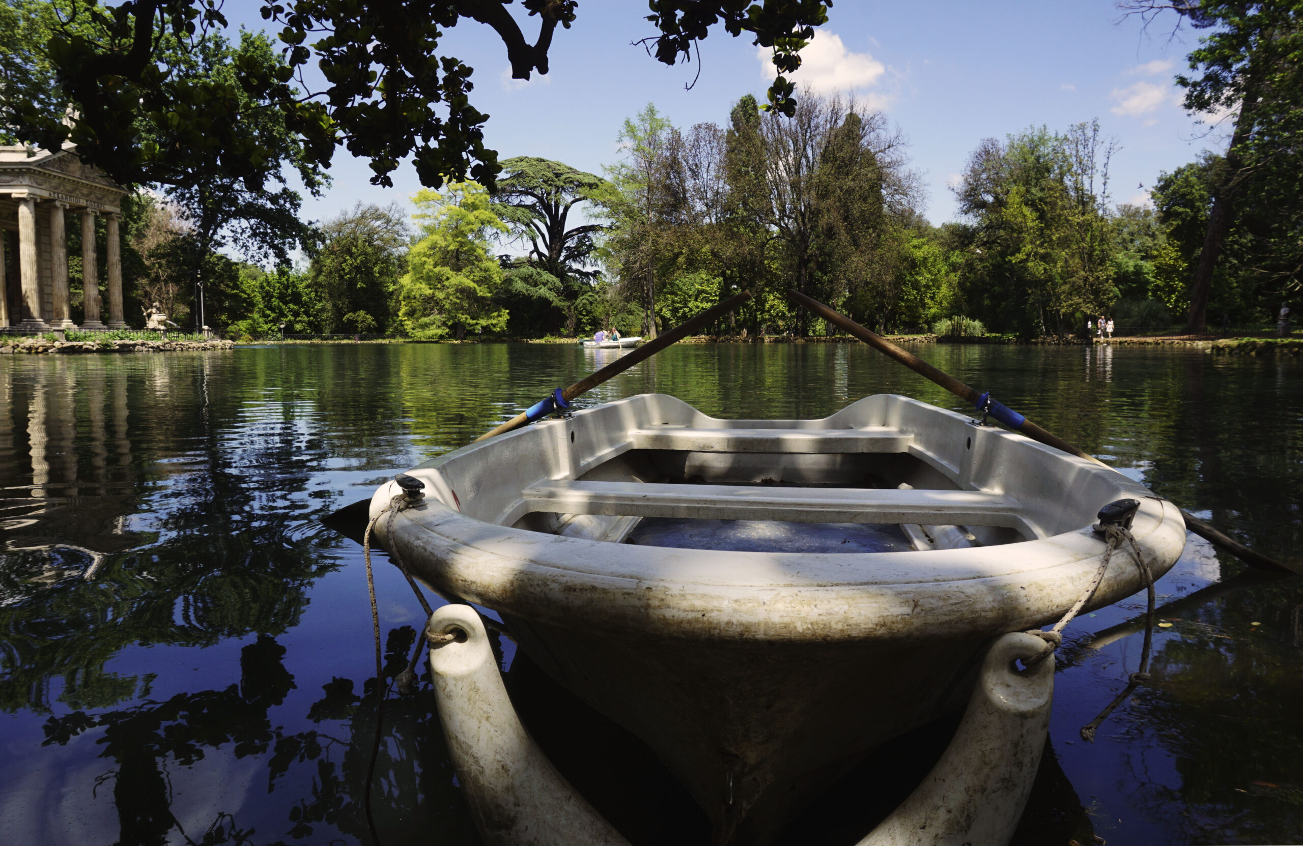 Tree-lined lake in Rome’s Villa Borghese gardens, with boats on the water.